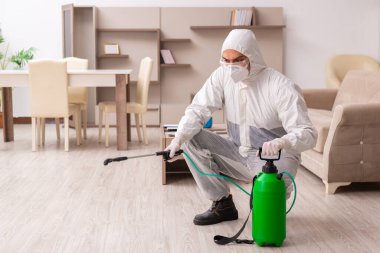 Genç erkek müteahhit evde haşere kontrolü yapıyor.