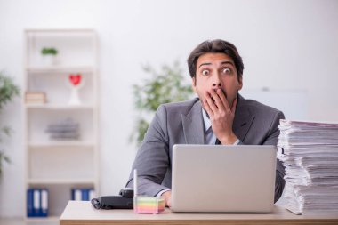 Genç bir erkek çalışan ve ofiste çok fazla iş var.