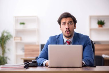 Genç erkek çalışan işyerinde oturuyor.