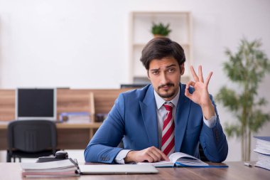 Genç erkek çalışan işyerinde oturuyor.