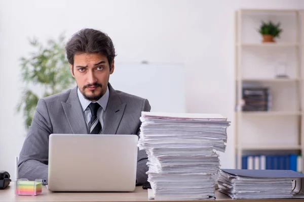 Joven empleado masculino y demasiado trabajo en la oficina — Foto de Stock