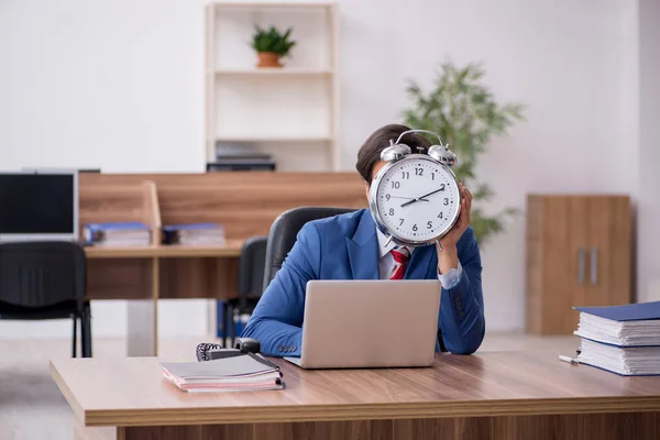 Jonge mannelijke werknemer in tijdmanagementconcept op de werkplek — Stockfoto