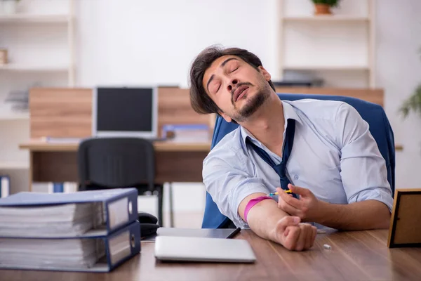 Giovane dipendente tossicodipendente maschile sul posto di lavoro — Foto Stock