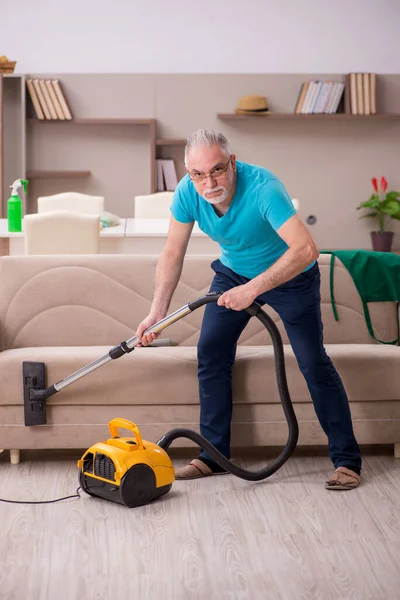 Oude man die het huis schoonmaakt — Stockfoto