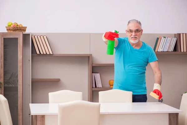 Oude man die het huis schoonmaakt — Stockfoto