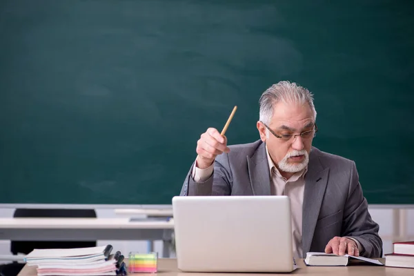 Gammal manlig lärare framför svarta tavlan — Stockfoto