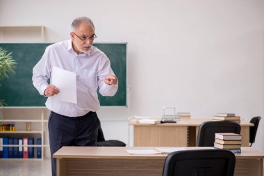 Tahtanın önünde yaşlı bir erkek öğretmen.