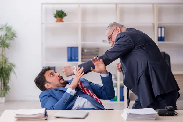 Velho chefe e jovem empregado masculino no conceito de bullying — Fotografia de Stock