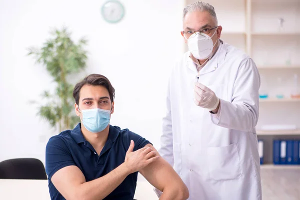 若い男性患者訪問古い男性医師で予防接種ce — ストック写真