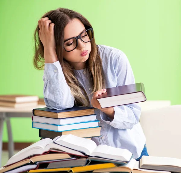 Jovem estudante se preparando para exames com muitos livros — Fotografia de Stock