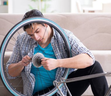 Evde bisiklet tamir eden genç bir adam.