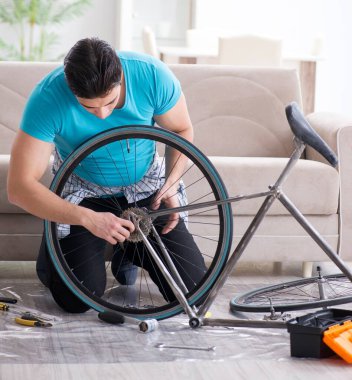Evde bisiklet tamir eden genç bir adam.