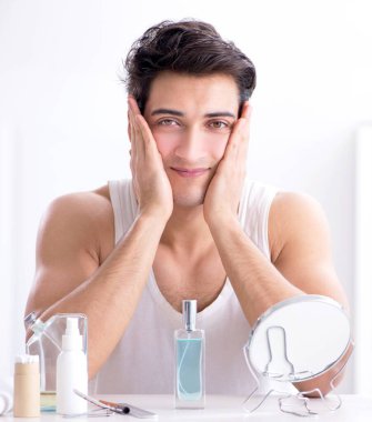 Genç yakışıklı adam aynaya bakıyor.