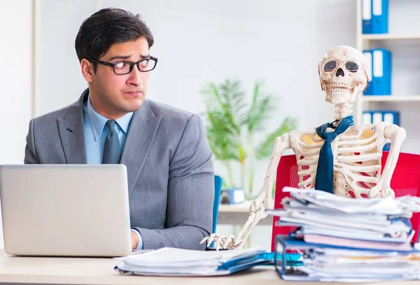 Бизнесмен, работающий со скелетом в офисе — стоковое фото