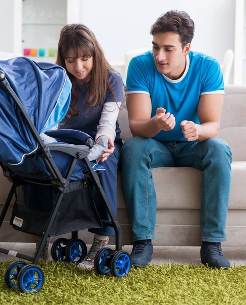 Unga föräldrar med sitt nyfödda barn i barnvagn sitter på th — Stockfoto