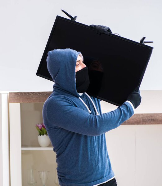 Man burglar stealing tv set from house