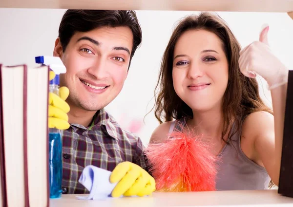 Esposa y marido limpiando polvo de la estantería — Foto de Stock