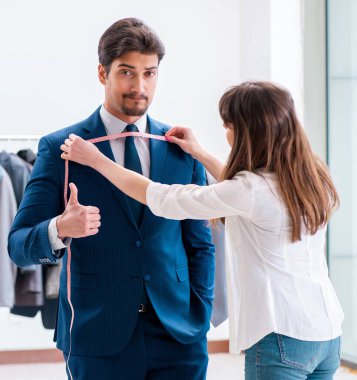 Profesyonel terzi resmi kıyafet için ölçü alıyor.