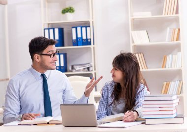 Erkek öğretim görevlisi bayan öğrenciye ders veriyor.