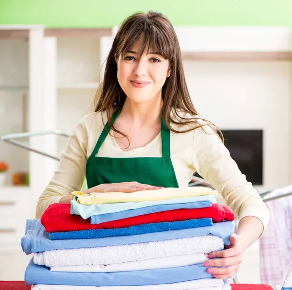 Jonge vrouw strijken kleding thuis — Stockfoto