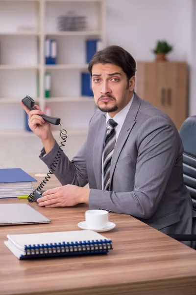 Ung attraktiv manlig anställd sitter på arbetsplatsen — Stockfoto