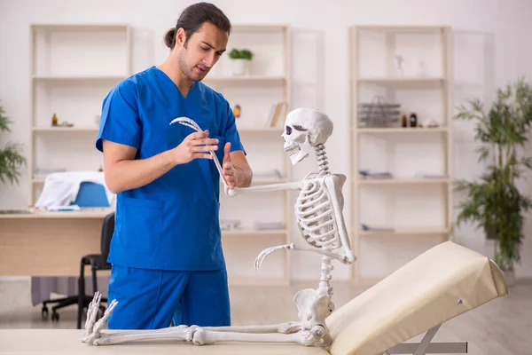 Молодой врач и пациент со скелетом в клинике — стоковое фото