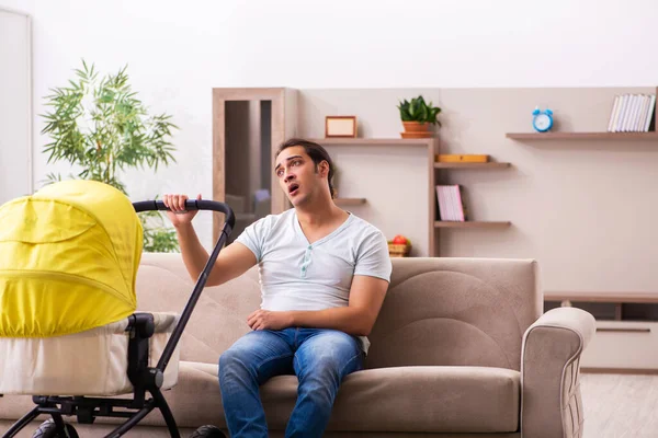 Jovem empreiteiro masculino cuidando de recém-nascido em casa — Fotografia de Stock