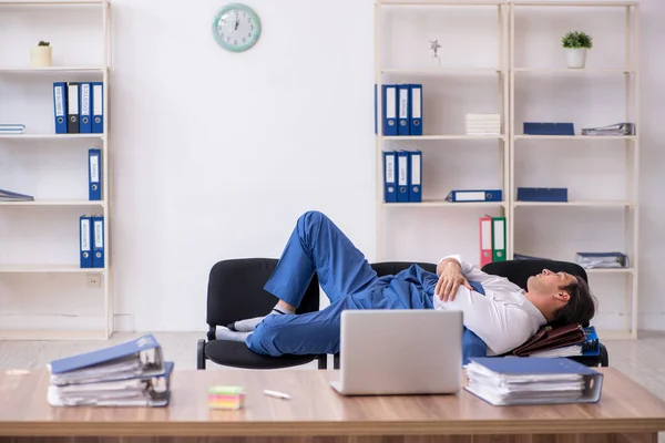 Jonge mannelijke werknemer slapen in het kantoor op stoelen — Stockfoto