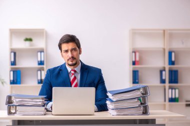 Ofisteki aşırı işten memnun olmayan genç bir erkek işçi.