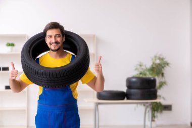 Atölyede lastiği olan genç bir erkek tamirci.