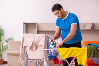 Genç adam evde ütü yapıyor.