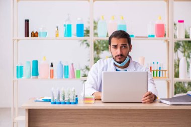 Genç erkek kimyager laboratuarda sabun test ediyor.