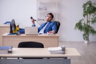 Genç erkek çalışan ofiste oturuyor.