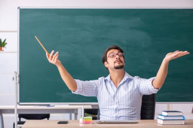 Tahtanın önündeki genç erkek öğretmen.
