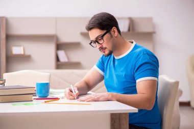 Evde okuyan genç bir erkek öğrenci.