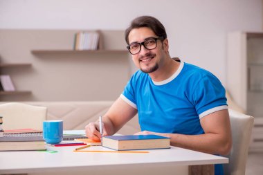 Evde okuyan genç bir erkek öğrenci.