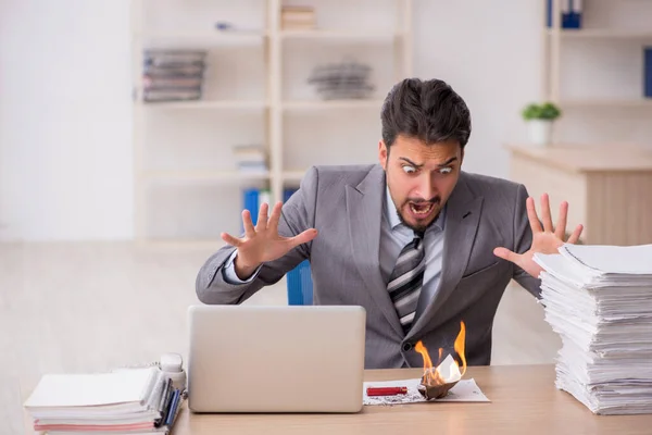 Jonge mannelijke werknemer ongelukkig met overmatig werk in het kantoor — Stockfoto