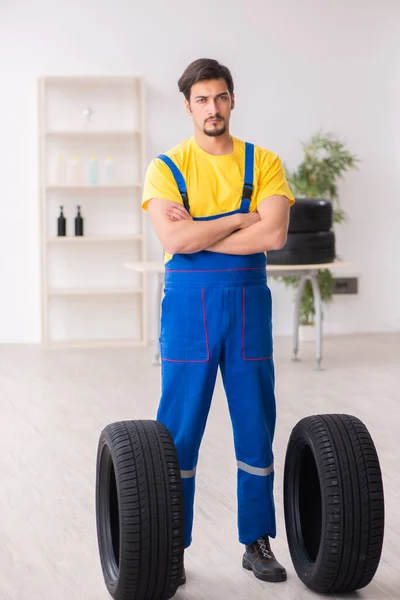 작업장에서 타이어를 사용하는 젊은 남자차고 노동자 — 스톡 사진