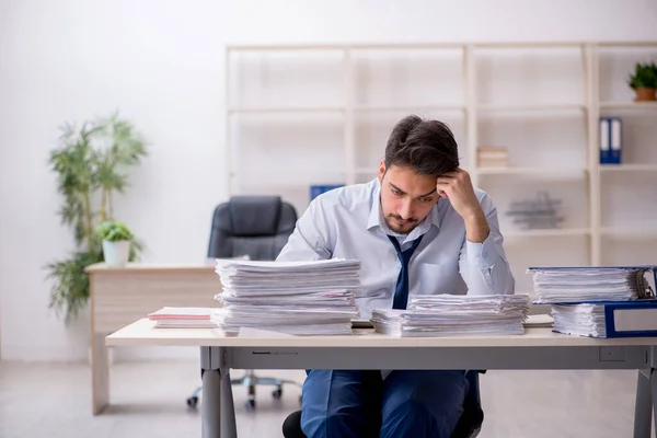 Jonge mannelijke werknemer ongelukkig met overmatig werk in het kantoor — Stockfoto