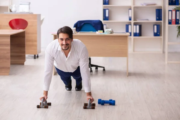 Young male employee doing sport exercises during break — Stock Photo, Image