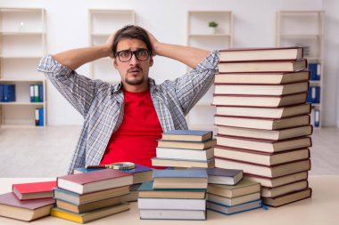 Genç bir erkek öğrenci ve sınıfta çok fazla kitap var.