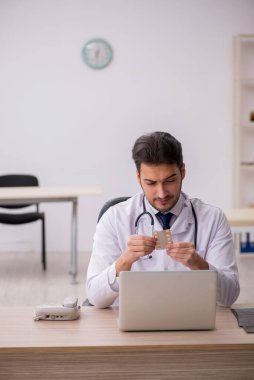 Klinikte ilaç tutan genç bir erkek doktor.
