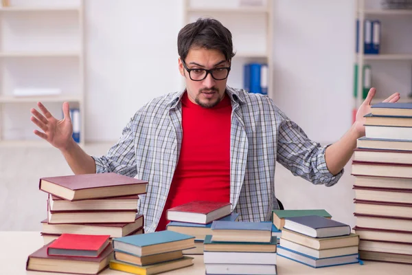 Giovane studente maschio e troppi libri in classe — Foto Stock