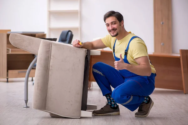 Joven carpintero masculino reparando sillón en la oficina —  Fotos de Stock