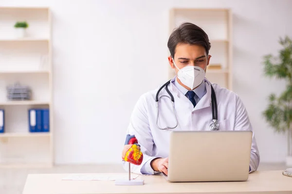 Genç erkek doktor kardiyolog pand sırasında klinikte çalışıyor. — Stok fotoğraf