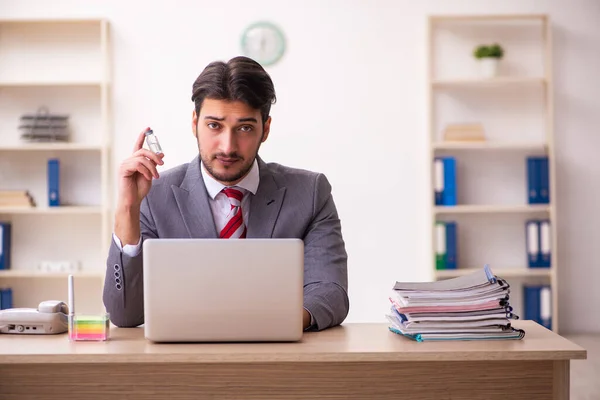 Jovem empresário empregado segurando frasco no escritório — Fotografia de Stock