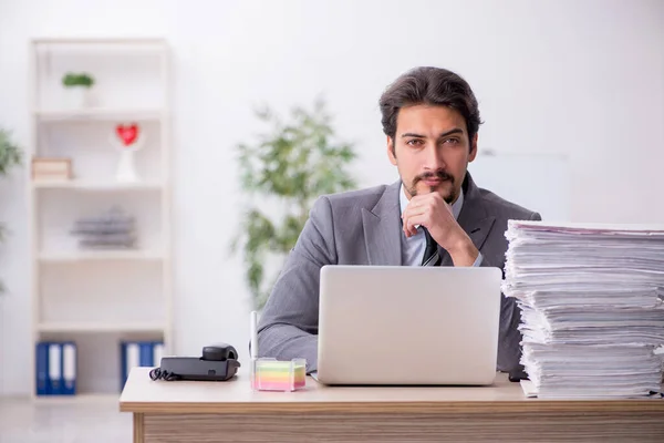 Ung manlig anställd och för mycket arbete på kontoret — Stockfoto