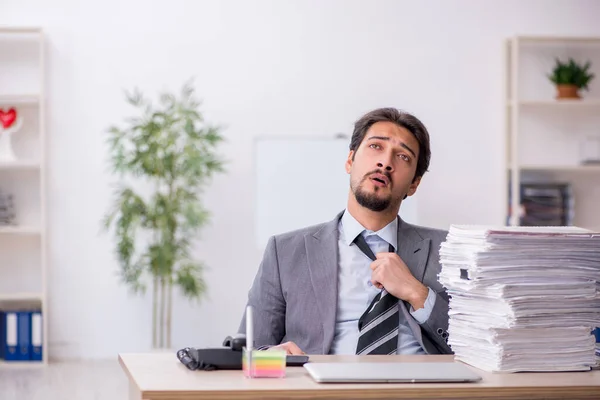 Joven empleado masculino y demasiado trabajo en la oficina — Foto de Stock