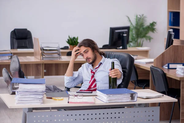 Junge männliche Angestellte trinkt Alkohol im Büro — Stockfoto