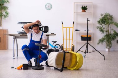 Genç erkek tamirci perambulator tamir ediyor.